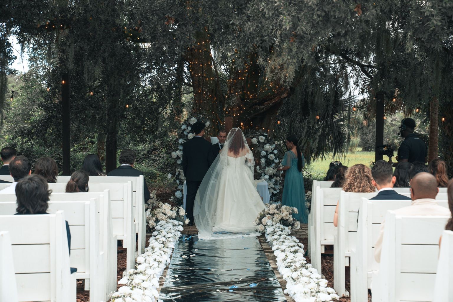 An outdoor wedding ceremony aisle lined with white florals